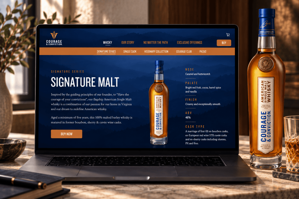 Laptop on a marble desk showing the Courage & Conviction Signature Malt product page in navy and copper, with the whisky bottle standing beside it